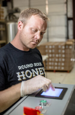 Round Rock Honey employee closely monitoring equiment in the factory.